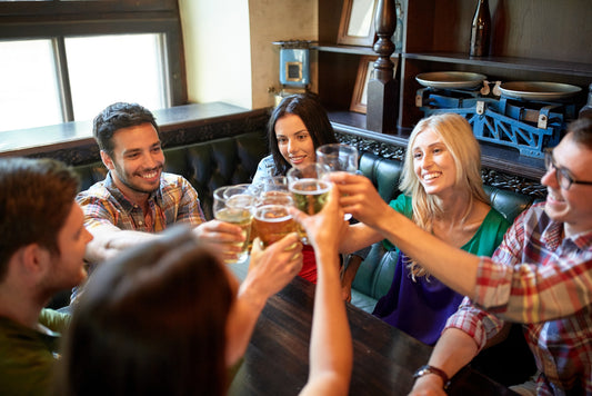 happy friends drinking beer and clinking their glasses at a bar