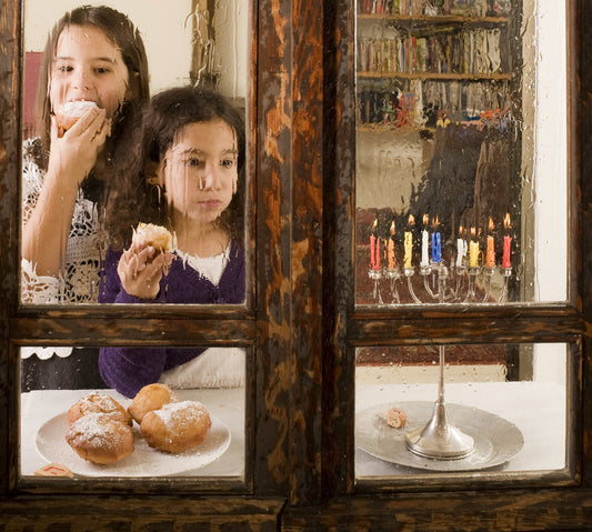 two young girls standing by a rain covered window eating deserts