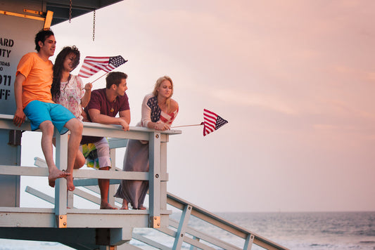 young people standing on a beach just before sunset