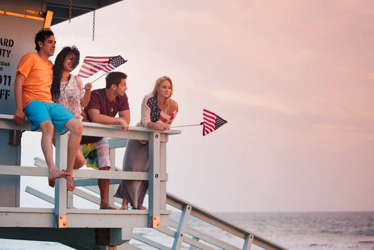 young people standing on a beach just before sunset