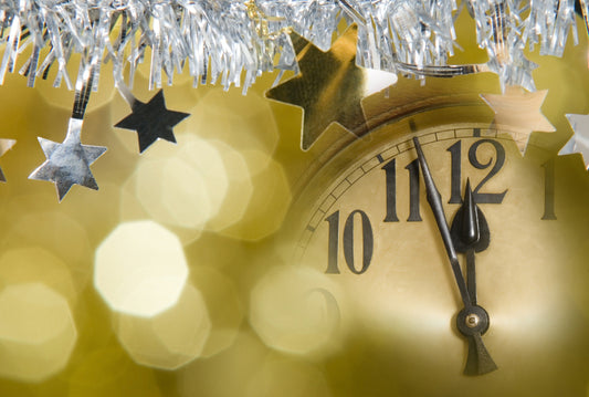 Clock counting down to midnight on New Year's Eve; silver stars in foreground
