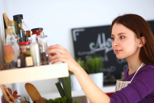 Young woman examines items on kitchen shelf