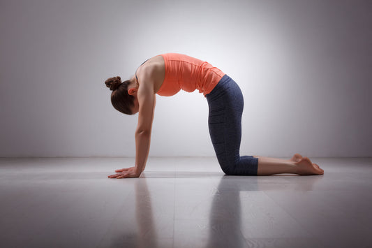 Female yogini practices asana marjariasana (cat pose)