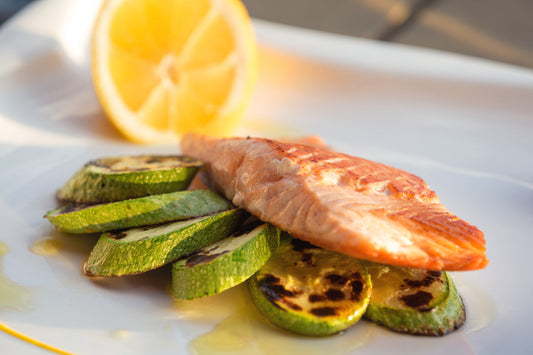 fish on a plate with cooked vegatables a slice of lemon