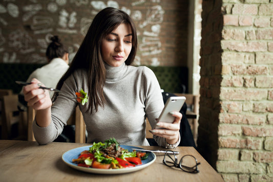 a woman eating a salad while looking at their phone