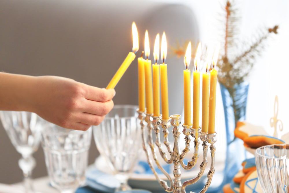 someone lighting candles on a table during Hannukah