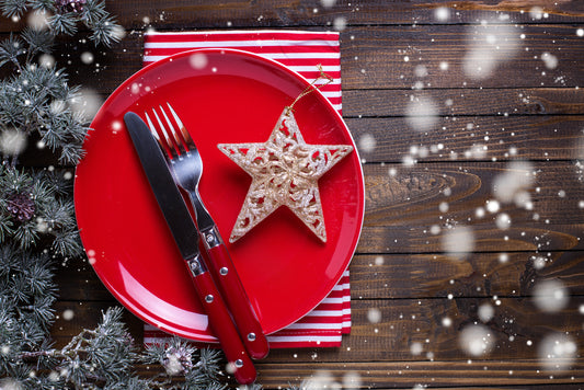 red plate with silverware and a star ornament on wood table