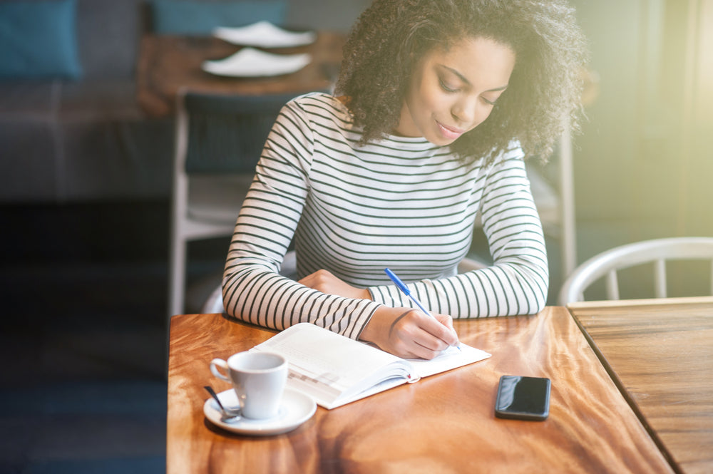 Young woman in cafe writes in her journal