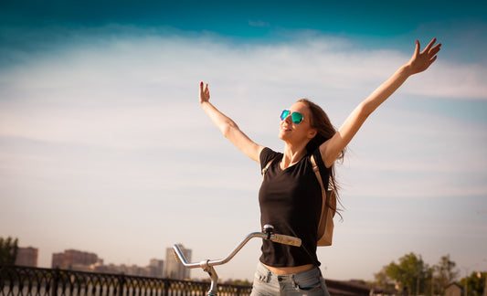 Brunette cyclist raises arms at end of a springtime ride in urban setting