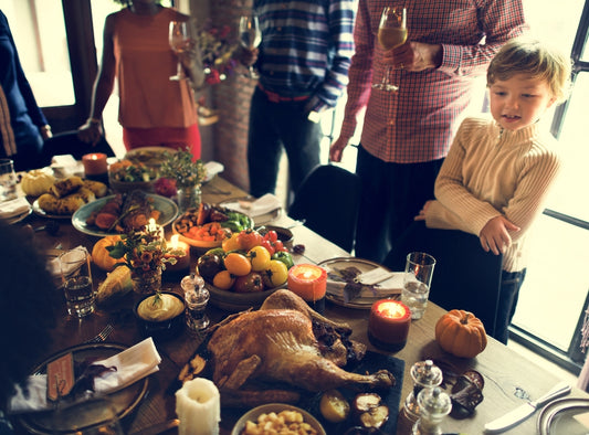 young child and family standing by dinner table full of food on Thanksgiving