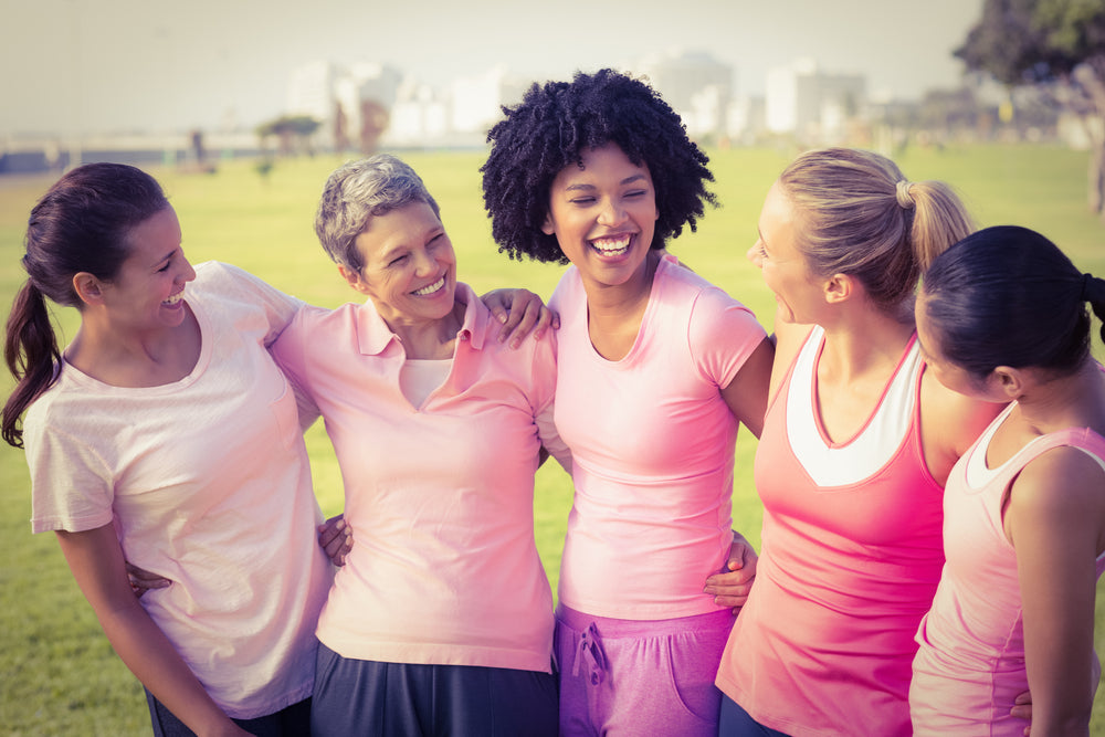 Five smiling women in workout clothes on athletic field