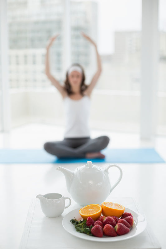 Young woman seated in yoga pose with healthy meal foreground