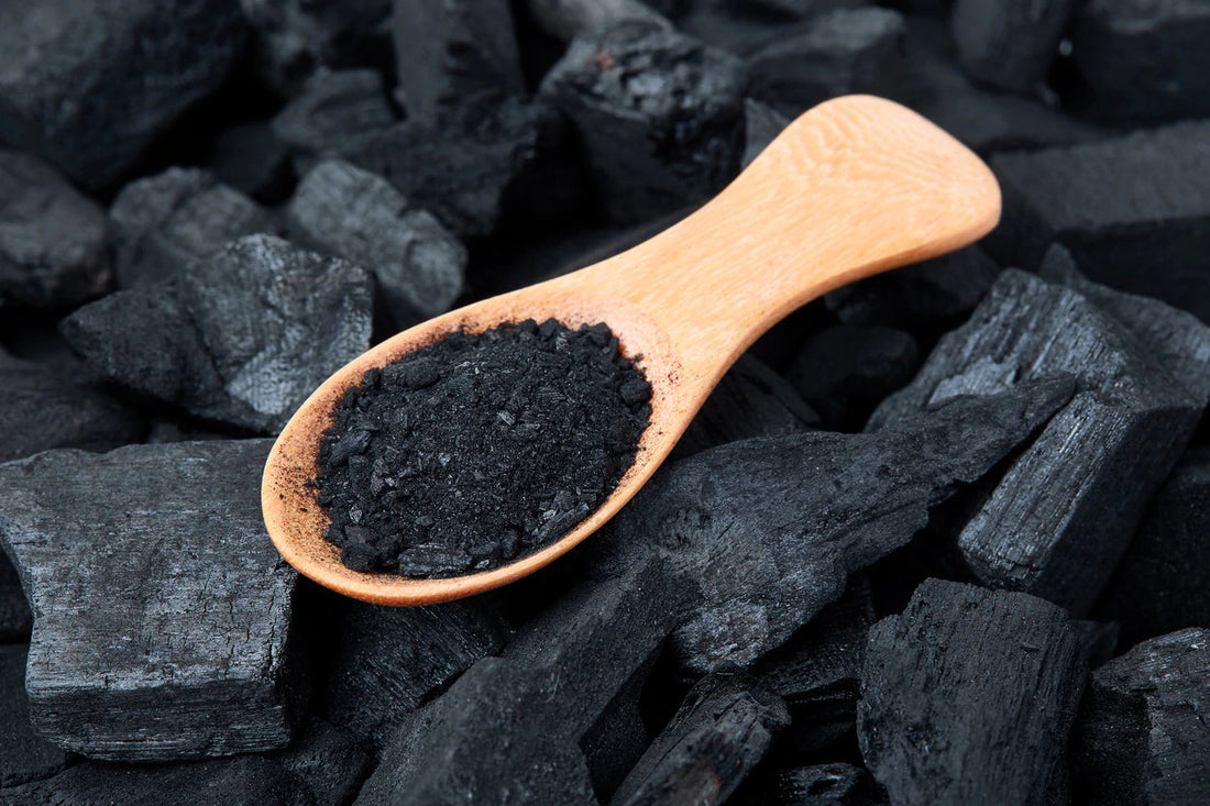 activated charcoal on a wooden spoon sitting on a pile of charcoal