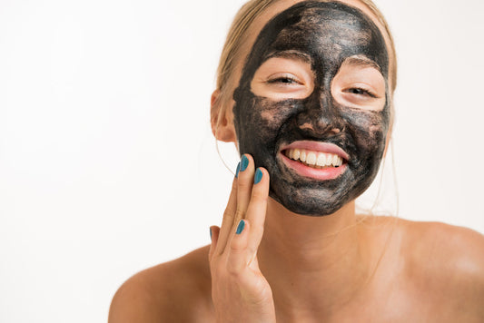 a woman using activated charcoal cream to exfloiate her face